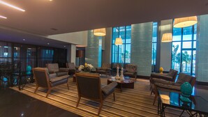 A spacious lobby with modern furnishings, large windows, and a striped carpet. - Mais Hotel Aeroporto Salvador (Lauro de Freitas)