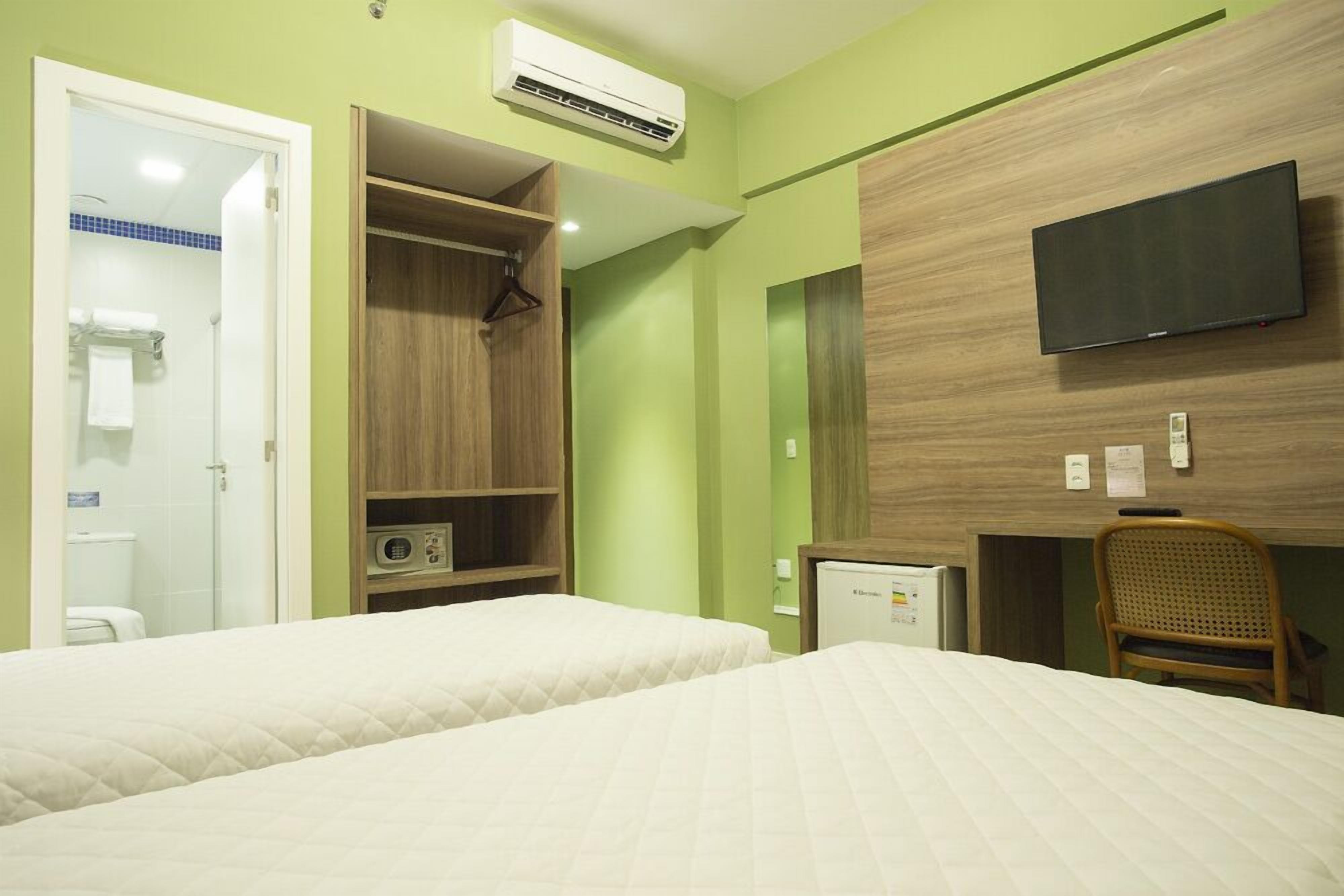 A hotel room with two beds, a wardrobe, a television, and a desk with a chair.