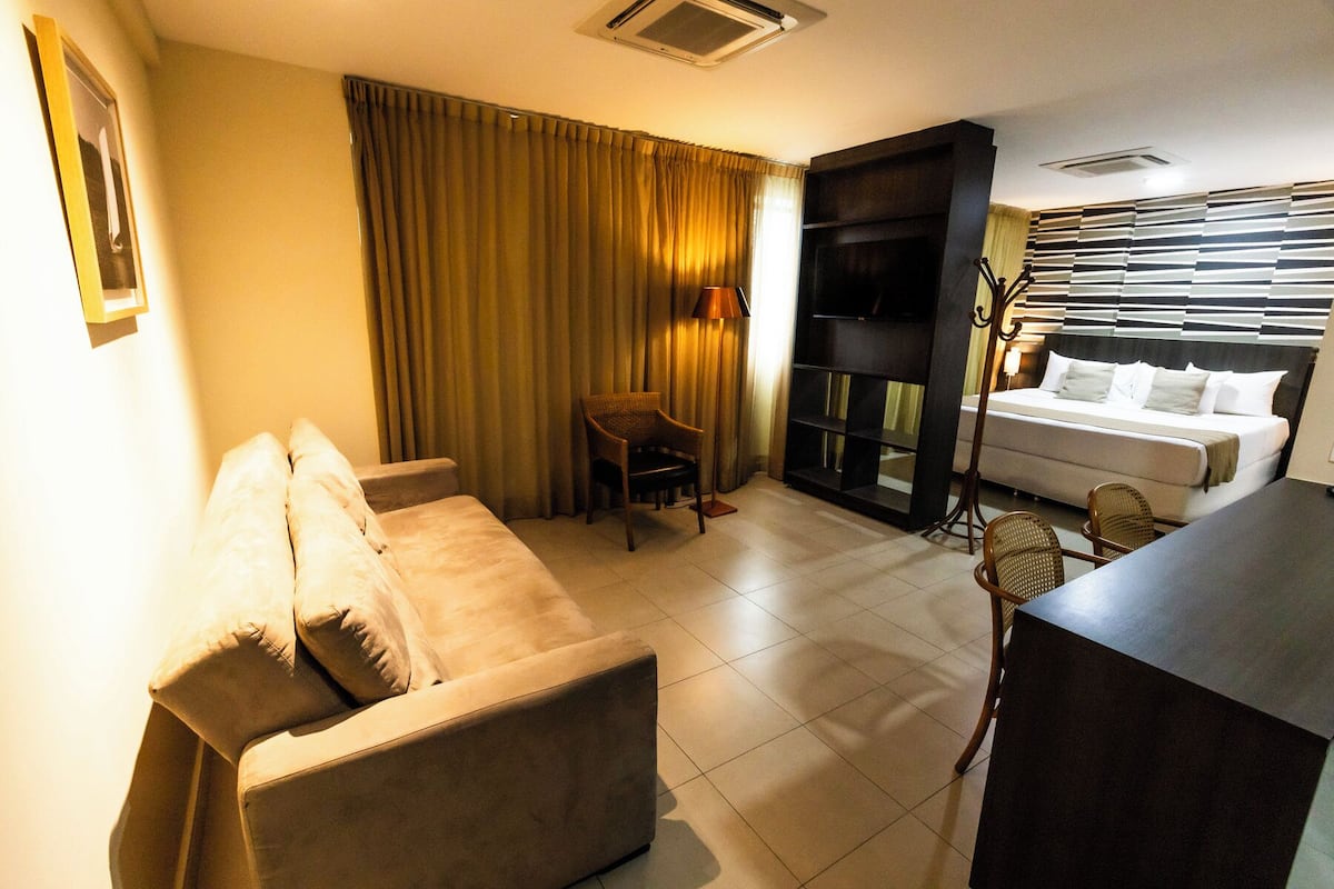 A hotel room with a sofa, a small table, a TV, and a bed.