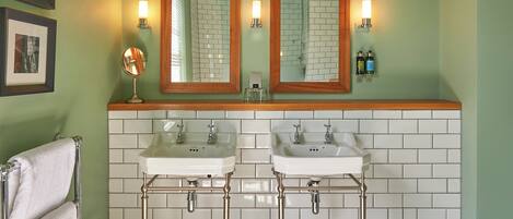 A bathroom with two sinks, a mirror, and wall-mounted lights.