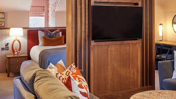 Quarto de hotel moderno com uma cama grande, um sofá, uma televisão e uma mesinha.