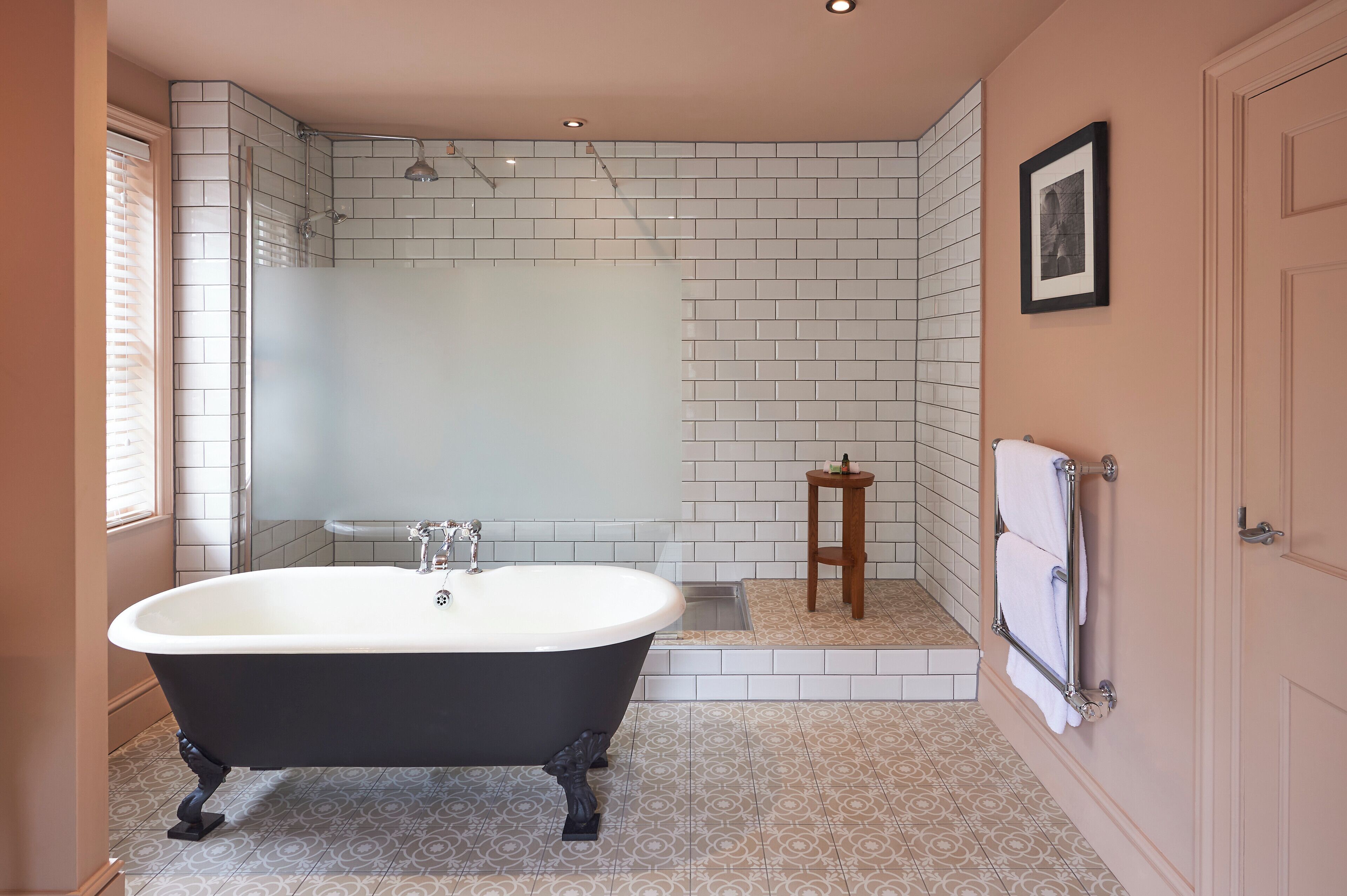 A bathroom with a freestanding bathtub, a shower enclosure, and a small wooden stool.
