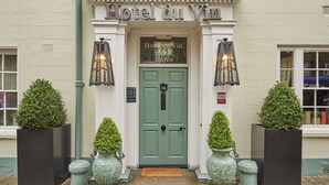L’entrée de l’hôtel Du Vin se distingue par sa porte verte, les deux arbustes taillés en forme décorative placés de part et d’autre, et l’enseigne au-dessus de la porte.