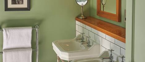 A bathroom with two sinks, a mirror, and a towel rack.