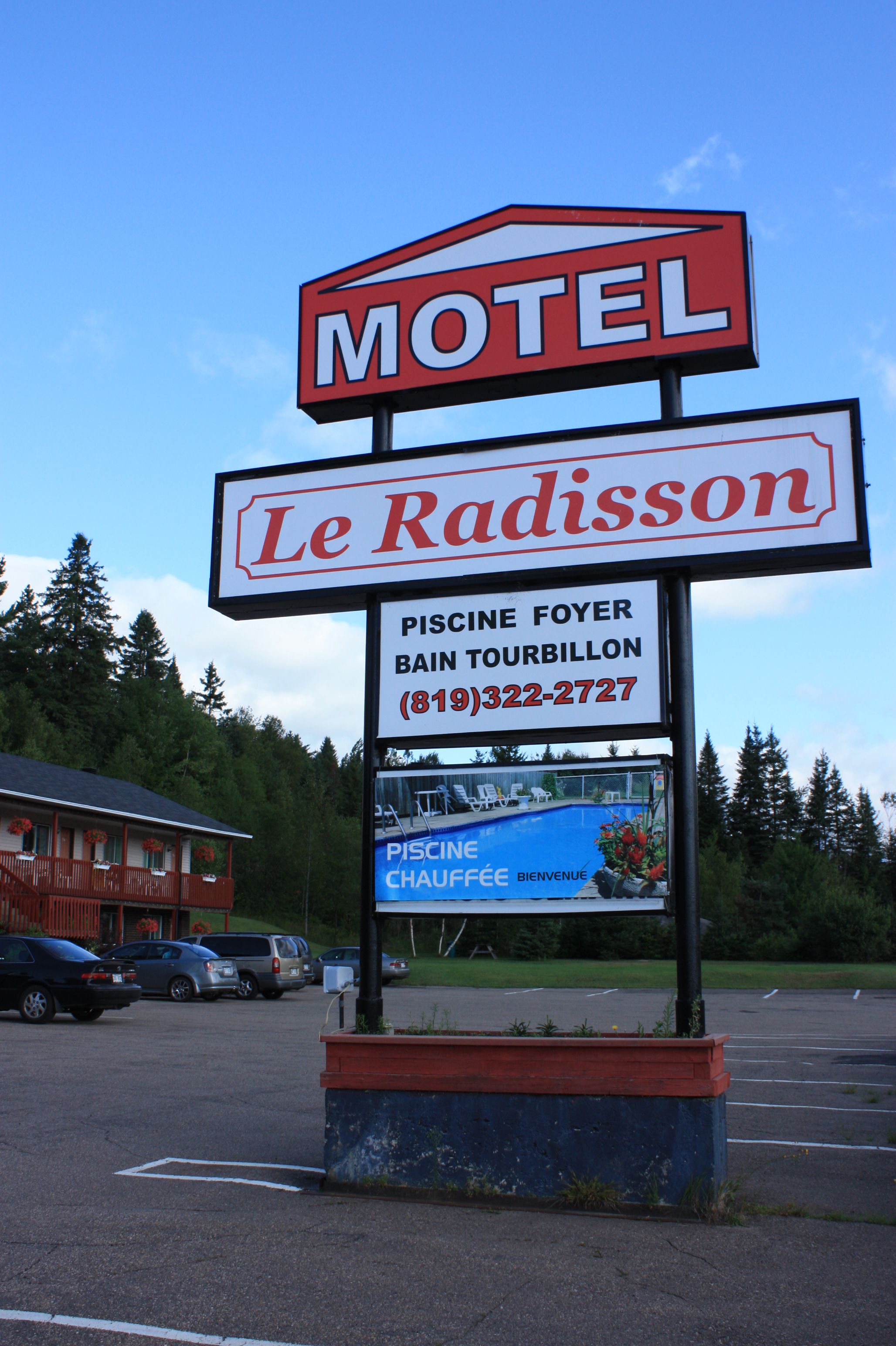 A motel sign with the name "Le Radisson" and a smaller sign advertising a pool and sauna.