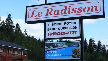 A motel sign with the name "Le Radisson" and a smaller sign advertising a pool and sauna.