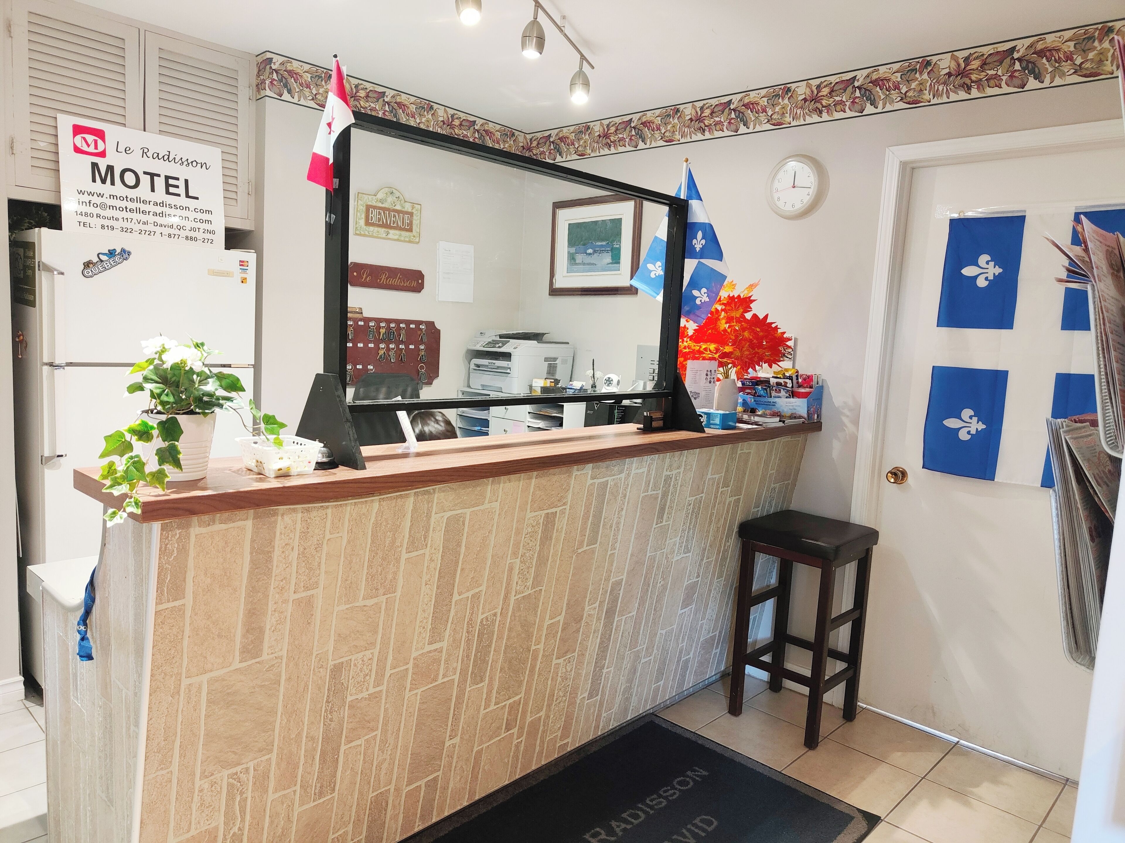 A reception desk with a mirror, a sign for Le Radisson Motel, a clock, and a door with blue and white decor.