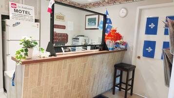 A reception desk with a mirror, a sign for Le Radisson Motel, a clock, and a door with blue and white decor.