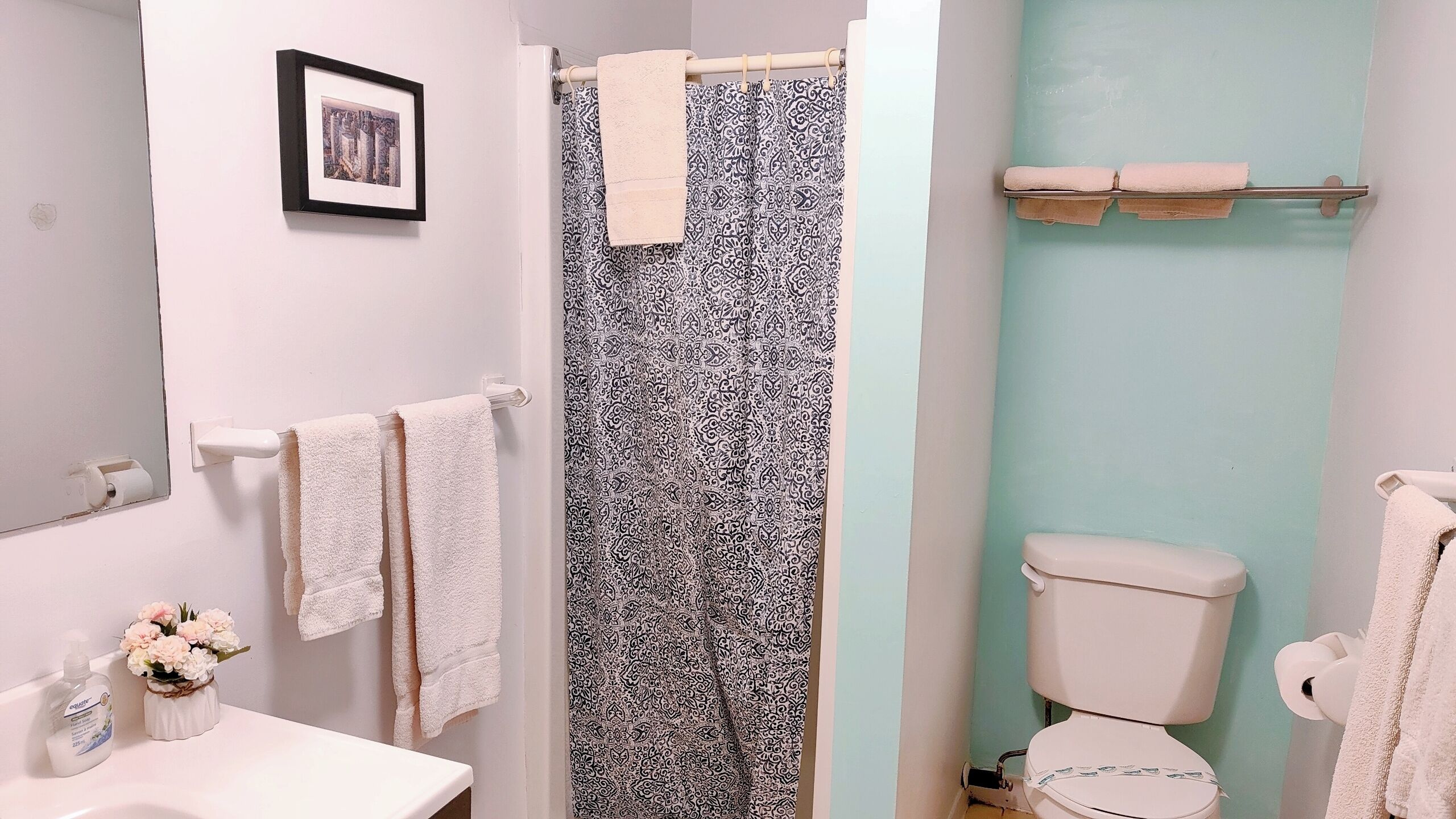 Un baño con cortina de ducha, inodoro, lavabo y toallas.