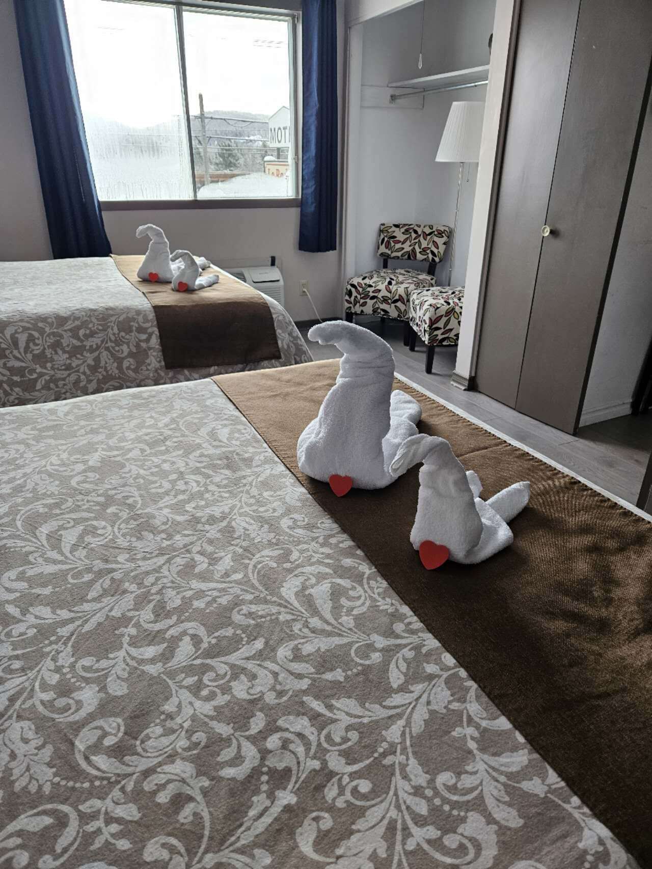 Una camera d'albergo con due letti, un divano, una poltrona e un armadio.