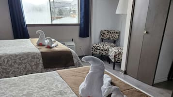 Una camera d'albergo con due letti, un divano, una poltrona e un armadio.