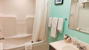A bathroom with a bathtub, a sink, a toilet, and a mirror.