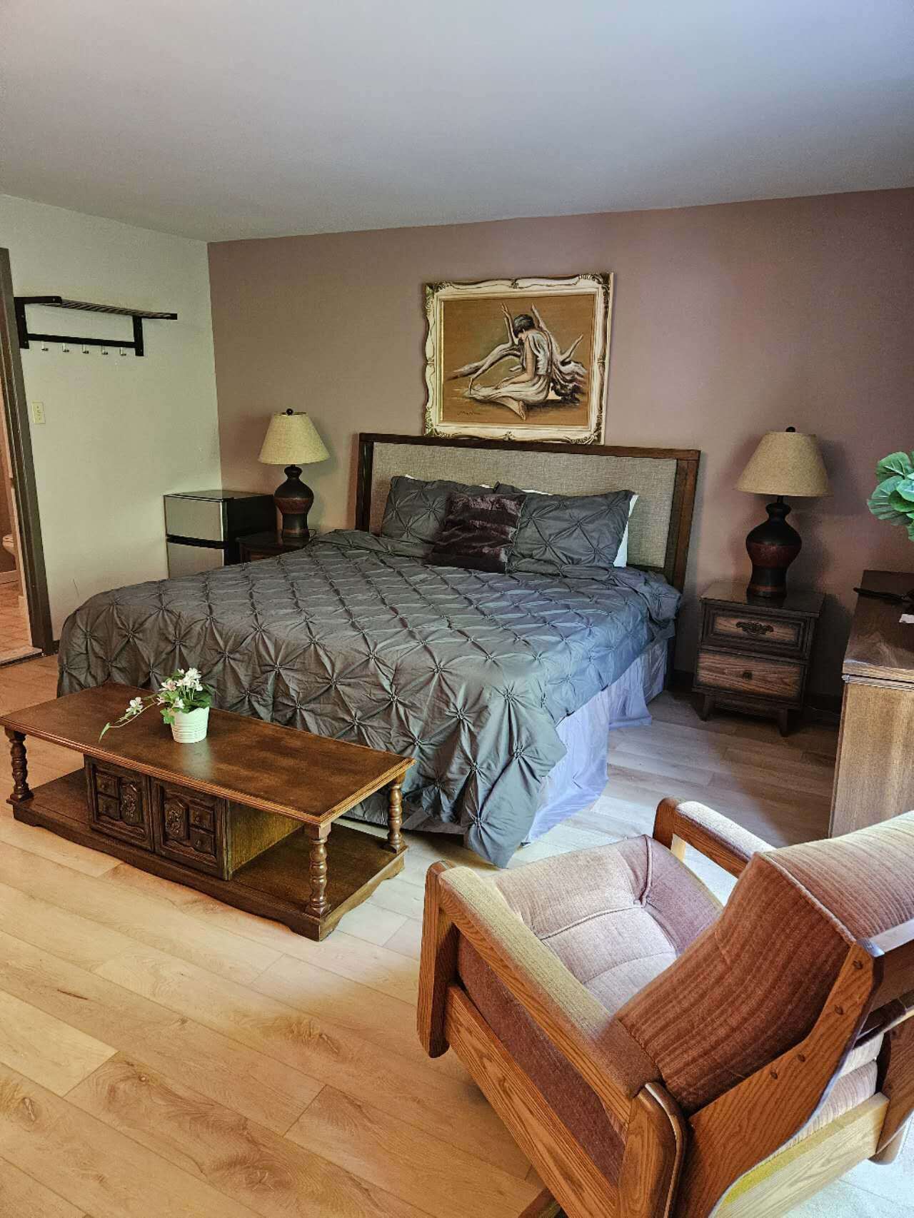 A bedroom with a large bed, two bedside tables, a wooden coffee table, and a chair.
