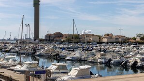 Un port de plaisance où sont amarrés de nombreux bateaux, une haute tour et, au loin, des immeubles d’habitation.
