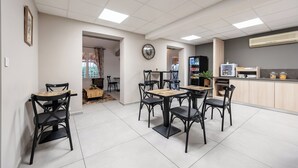 Un espace repas moderne doté d’un haut plafond, d’un éclairage encastré et d’un coin cuisine équipé d’un réfrigérateur et d’un four à micro-ondes.