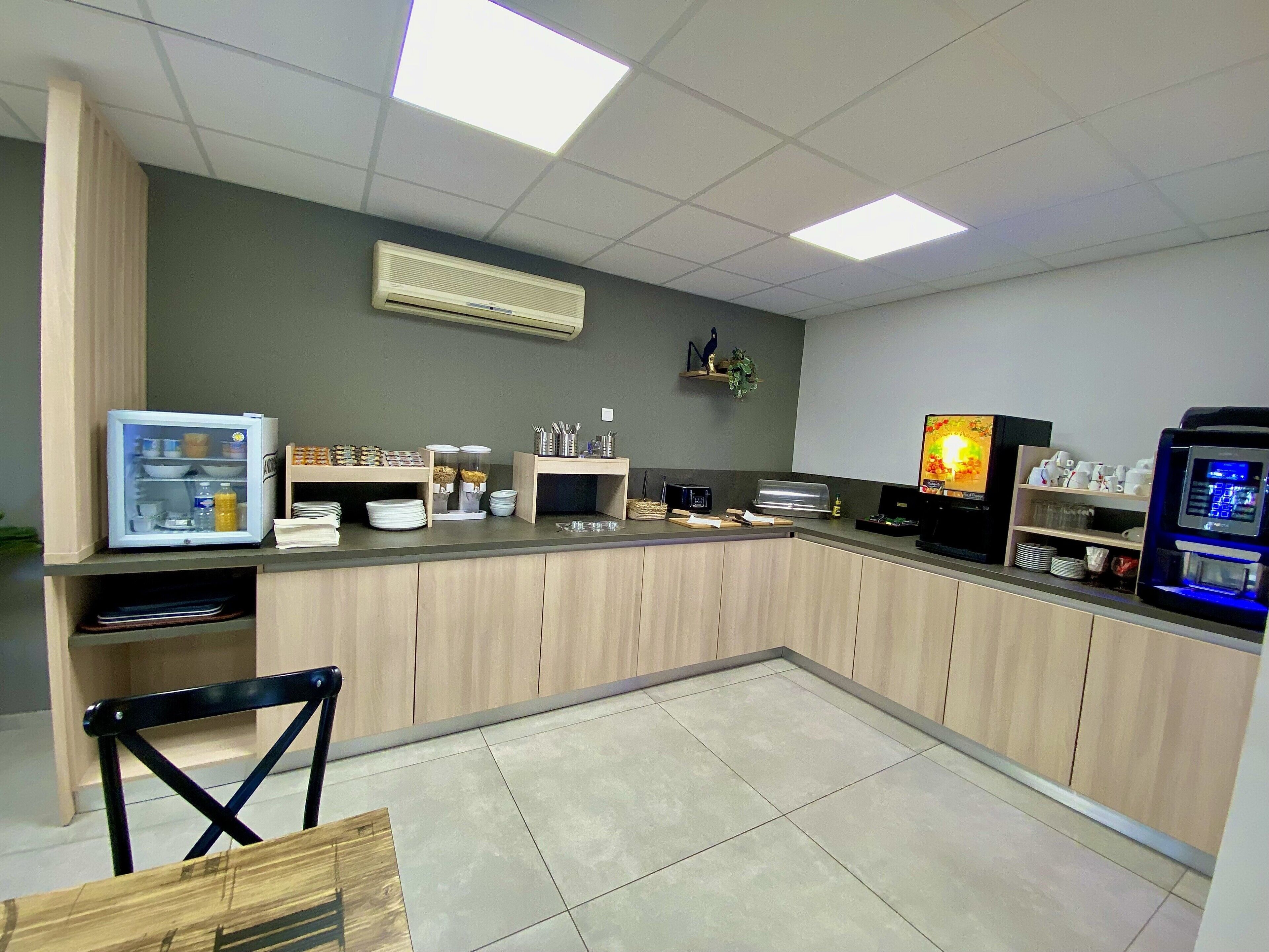 Une cuisine moderne équipée d’un réfrigérateur, d’un four à micro-ondes et d’une machine à café intégrés.