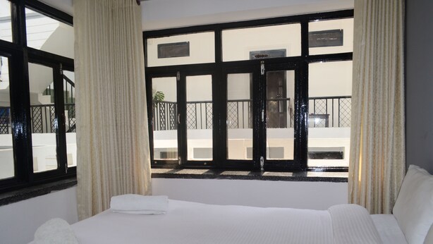 A hotel room with a large bed, a view of the balcony, and a door to the outside. - Holy Lodge (Kathmandu)