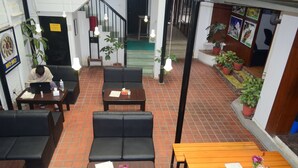 A restaurant with black leather sofas, wooden tables, and potted plants. - Holy Lodge (Kathmandu)