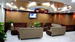 A lobby with sofas, a TV, and decorative plants. - Hotel Sweet Dream (Dhaka)