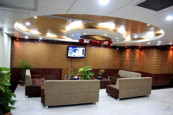 A lobby with sofas, a TV, and decorative plants. - Hotel Sweet Dream (Dhaka)