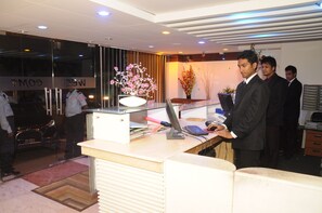 A reception desk with a computer, a vase of flowers, and a car parked outside. - Hotel Sweet Dream (Dhaka)