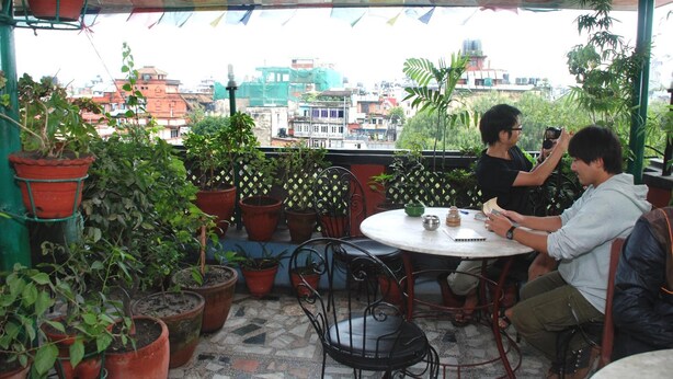 Una terrazza con piante in vaso, un tavolo rotondo e sedie.