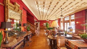 A spacious lobby with a high ceiling, ornate wooden furniture, and large windows allowing natural light. - Stockyards Hotel (Fort Worth)
