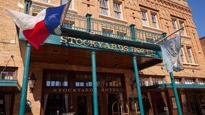 The Stockyards Hotel with a prominent Texan flag and a signboard displaying the hotel's name. - Stockyards Hotel (Fort Worth)
