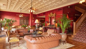 A spacious lobby with leather sofas, a grand staircase, and a large mirror. - Stockyards Hotel (Fort Worth)