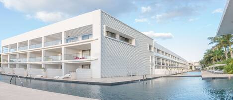 A modern hotel with a pool, multiple balconies, and a unique patterned facade.
