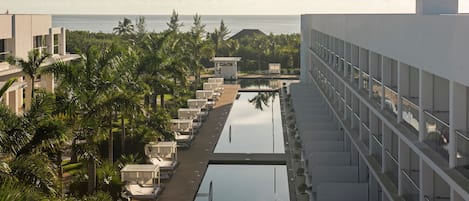 Un resort con piscina, palmeras y vista al océano.