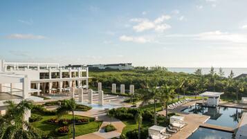 A resort with a large pool area, palm trees, and a modern building with multiple floors.