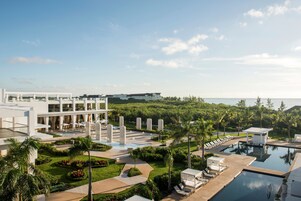 A resort with a large pool area, palm trees, and a modern building with multiple floors.