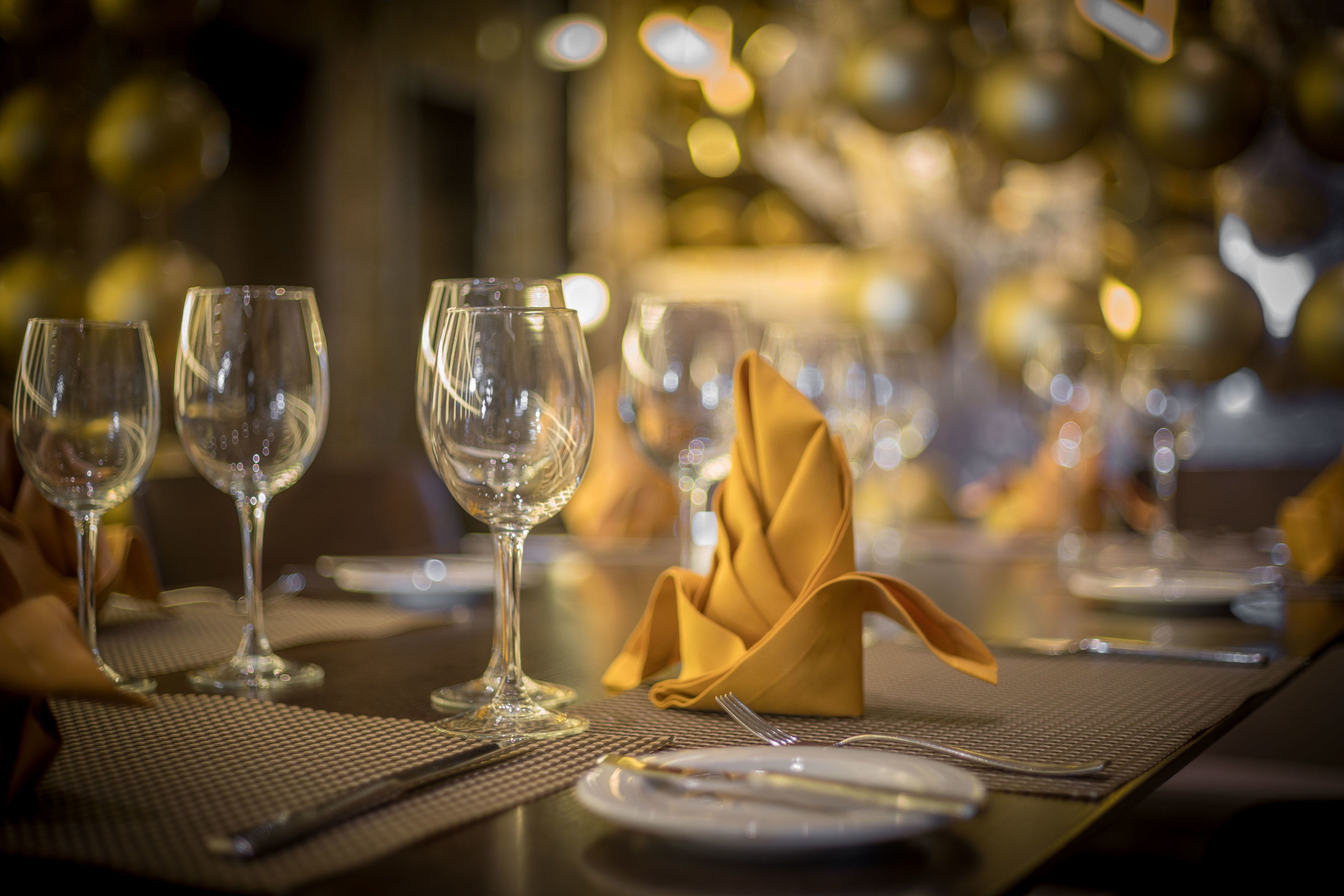 A dining table set with wine glasses, a folded napkin, and cutlery.