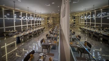 Un restaurante amplio con varias mesas y sillas, un suelo de mármol pulido y un candelabro moderno.