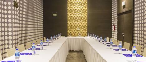 A conference room with a long table, chairs, water bottles, and a decorative wall.