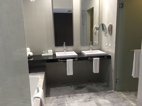 Un baño moderno con dos lavamanos, un espejo grande y una bañera.