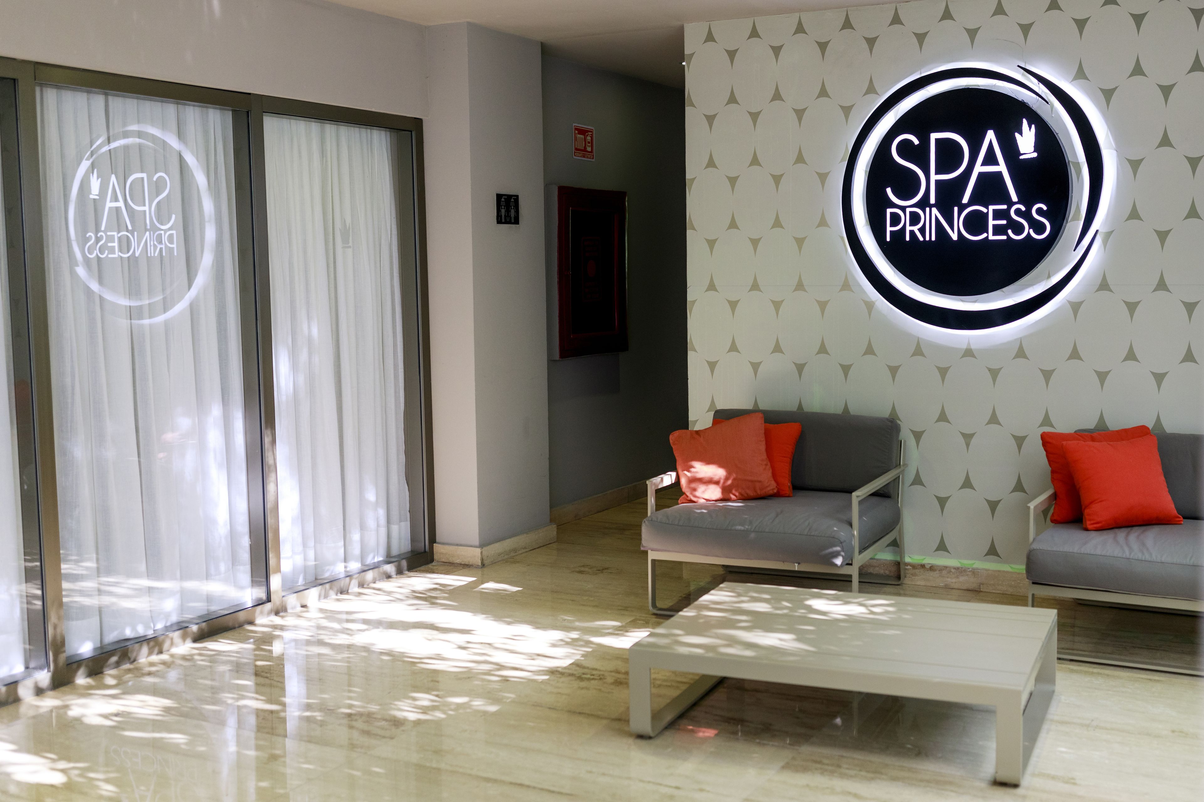 A modern spa room with a sofa, a coffee table, and a wall with a spa logo.