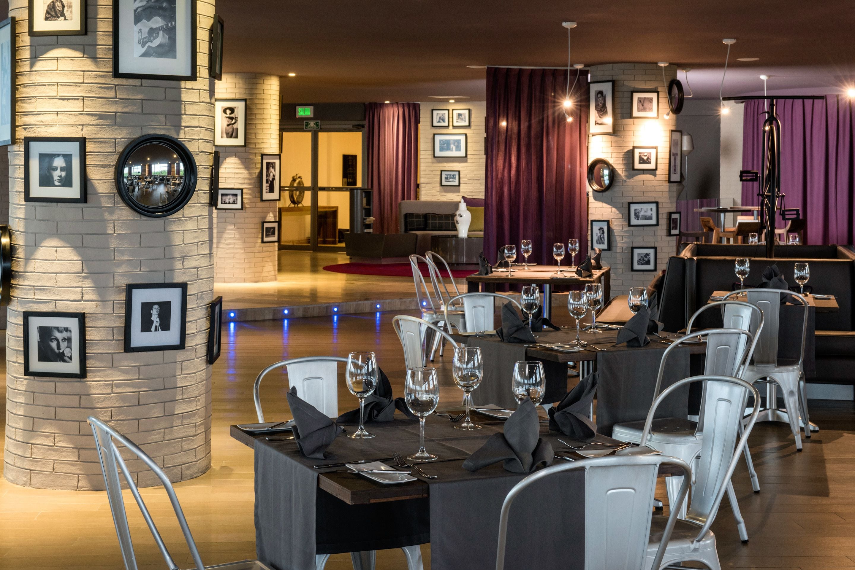 A restaurant with round tables, white chairs, and framed pictures on the walls.