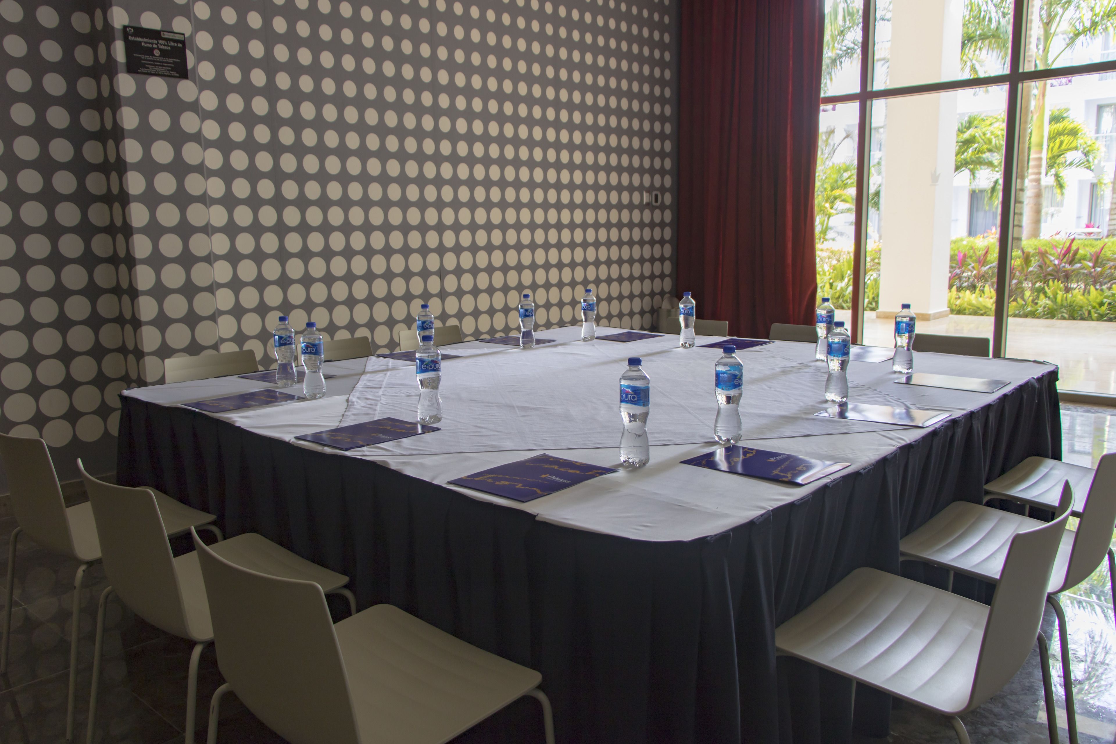 A conference room with a large table, chairs, water bottles, and nameplates.