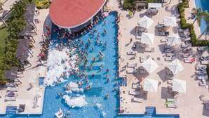 An aerial view of a resort with a large central pool surrounded by lounge areas and palm trees. - Platinum Yucatan Princess Adults Only - All Inclusive  (Playa del Carmen)