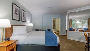 A hotel room with a large bed, bedside tables, a desk, and a seating area with a view of the outdoors.