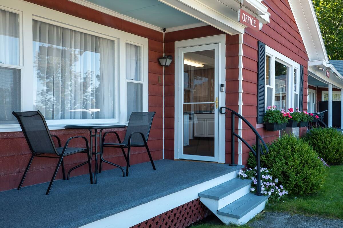 A red building with a porch, a table with chairs, and a sign that says "OFFICE".