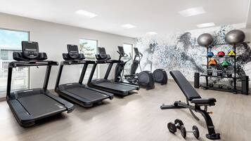 A gym with treadmills, a bench, dumbbells, and exercise balls.