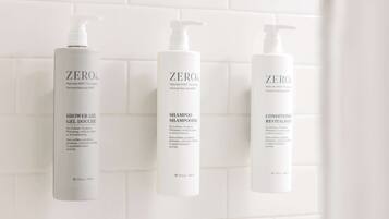 Three bottles of ZERO® products: shower gel, shampoo, and conditioner, all labeled as 'Naturally KIND' and free from sulfates, parabens, phthalates, artificial colors, or animal testing.