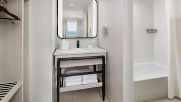 Un baño moderno con un tocador blanco, un espejo grande, una bañera y una cortina de ducha.