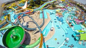 Un parque acuático con múltiples toboganes y piscinas, incluyendo un tobogán de agua grande de color verde y un río lento.