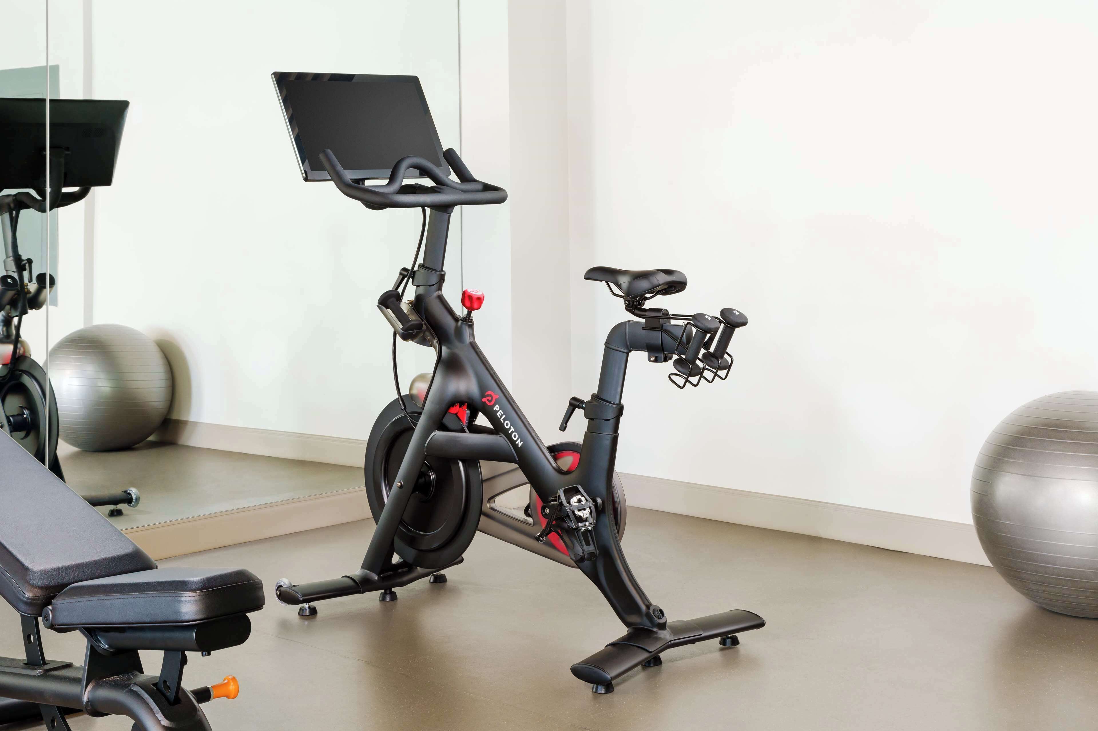 A stationary bike with a digital display, a bench, and exercise balls in a room.