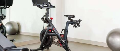 A stationary bike with a digital display, a bench, and exercise balls in a room.
