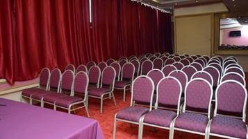 A conference room with rows of purple chairs and a table covered with a purple tablecloth.